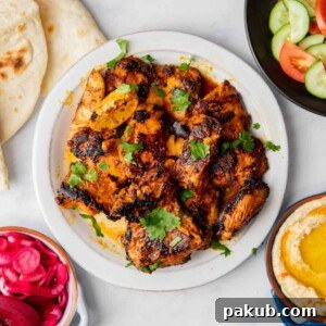 Chicken Shawarma laid out on a table along with pita, hummus, veggies, pickled beets and onions