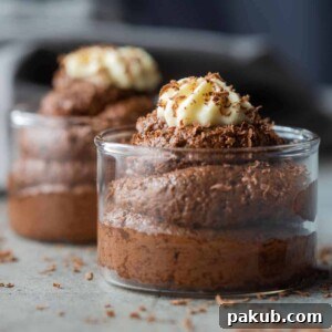 eggless chocolate mousse served in glass jars topped with whipped cream and a sprinkle of grated chocolate