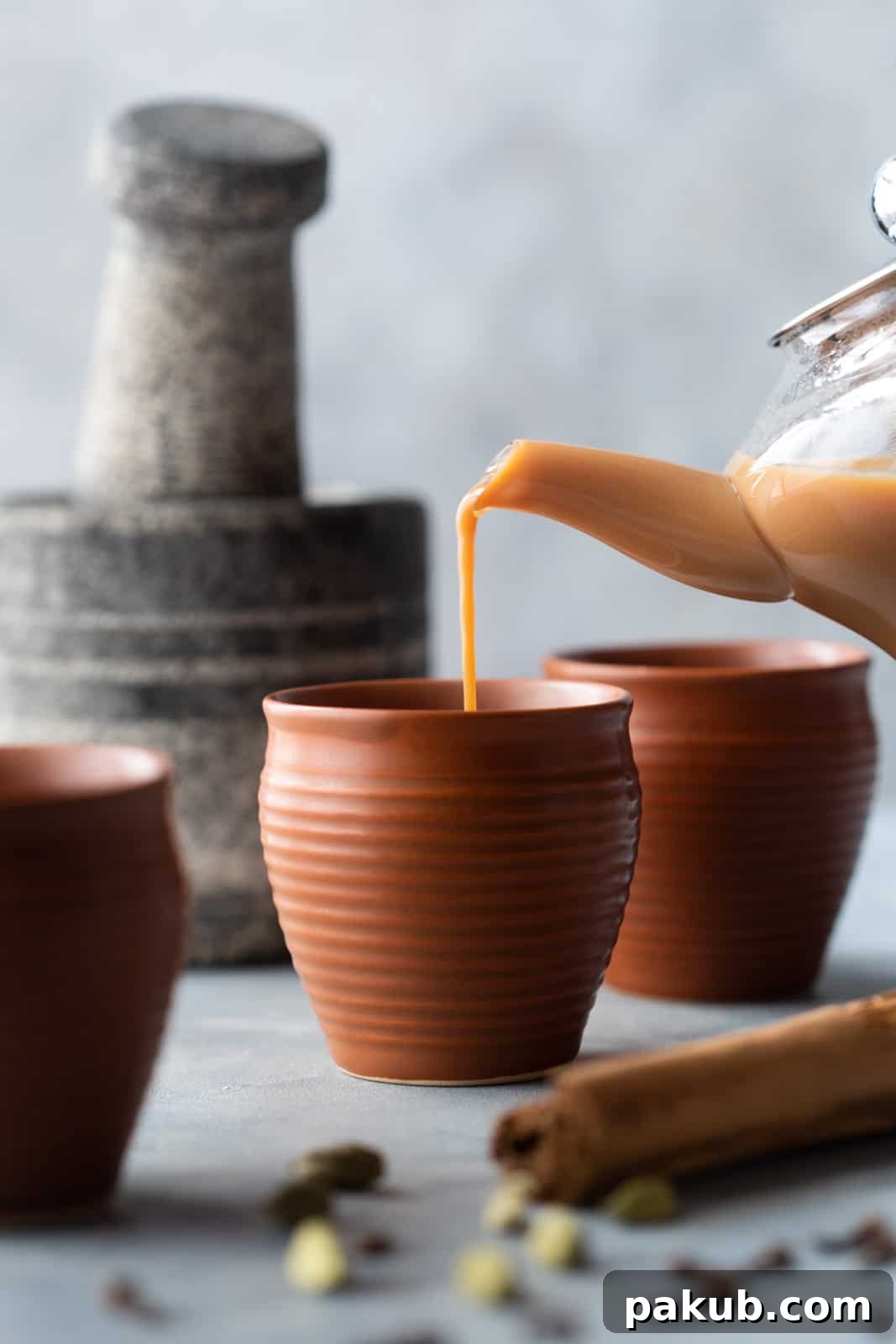 Chai Secrets Revealed 5 Recipes to Master 2 Pouring hot Indian chai into elegant cups, showcasing the rich, inviting color of traditional tea.