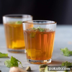 Sulaimani Chai beautifully presented in small traditional glasses, with lemon and mint garnish.