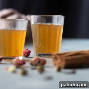 Kashmiri Kahwa presented in small, clear tea glasses, garnished with delicate saffron strands and whole spices.