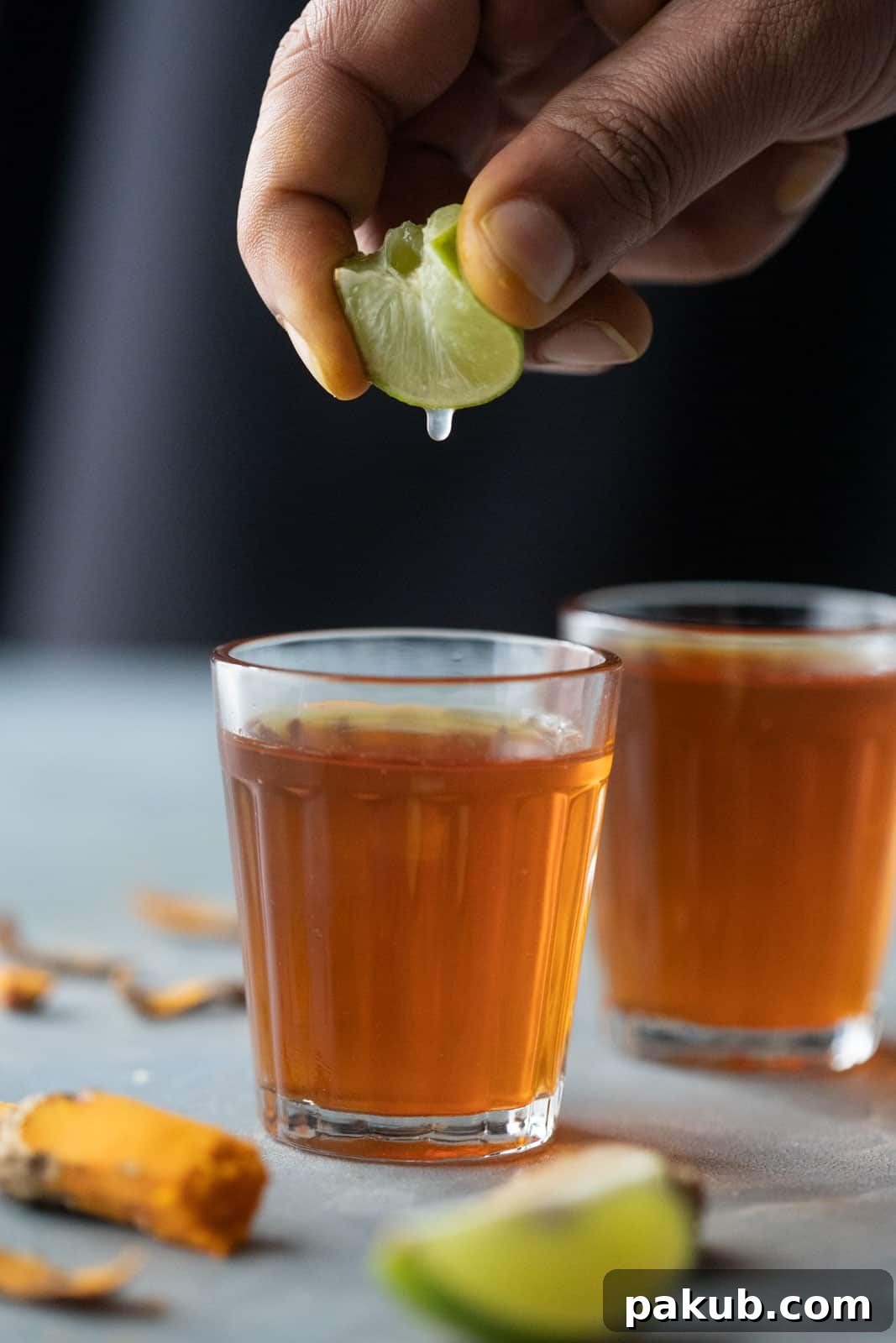 Chai Secrets Revealed 5 Recipes to Master 12 A hand squeezing fresh lemon into a vibrant golden turmeric tea, highlighting its healthful ingredients.