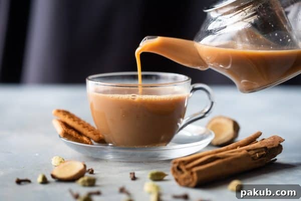 Chai Secrets Revealed 5 Recipes to Master 3 Freshly brewed Ginger Chai being elegantly poured into a cup from a traditional kettle, emphasizing warmth and comfort.