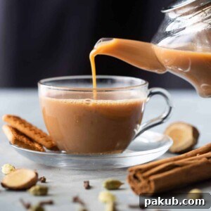 Ginger Chai being poured into a delicate cup from a rustic kettle, highlighting its golden hue.