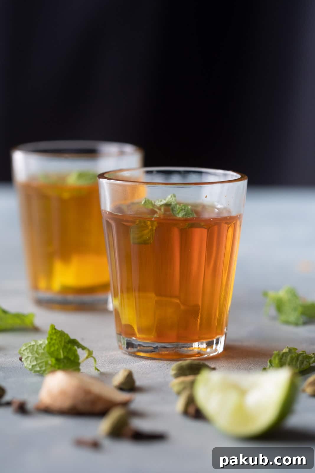 Chai Secrets Revealed 5 Recipes to Master 8 Clear Sulaimani Chai served in small elegant glasses, garnished with fresh mint and a lemon slice.