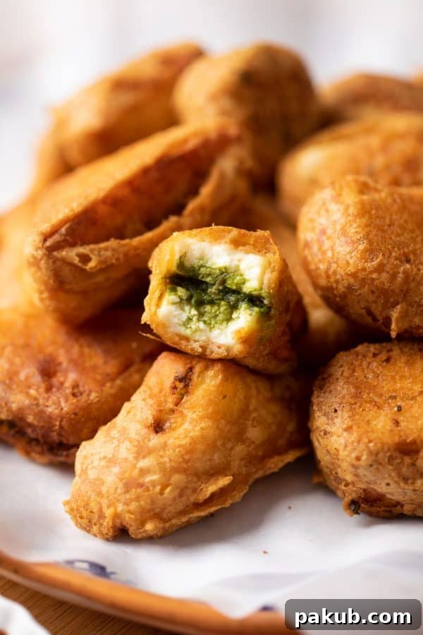 Chutney sandwich paneer pakora bite on a stack of paneer pakoras
