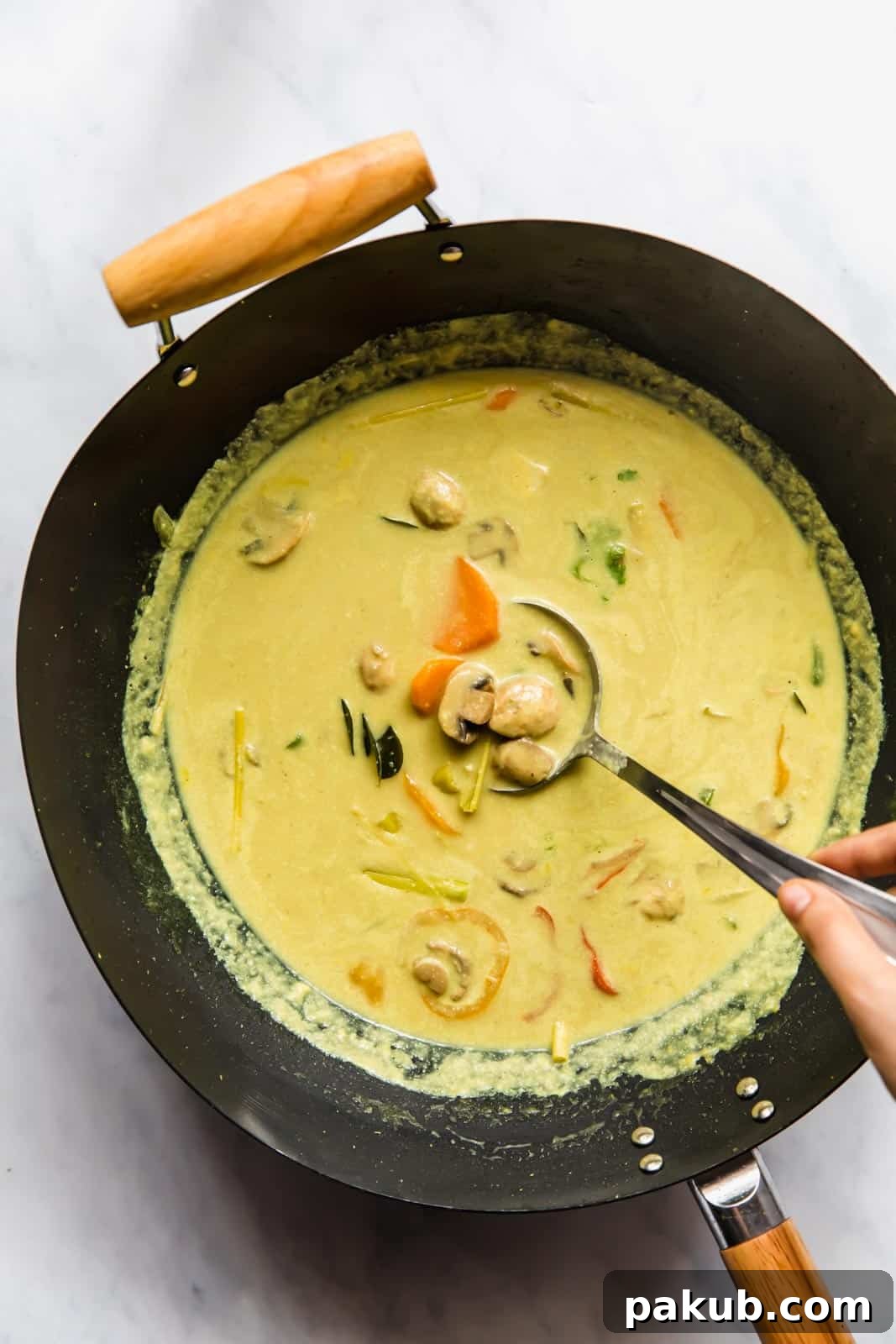 Khow Suey curry simmering in a wok, showing the rich, golden broth.
