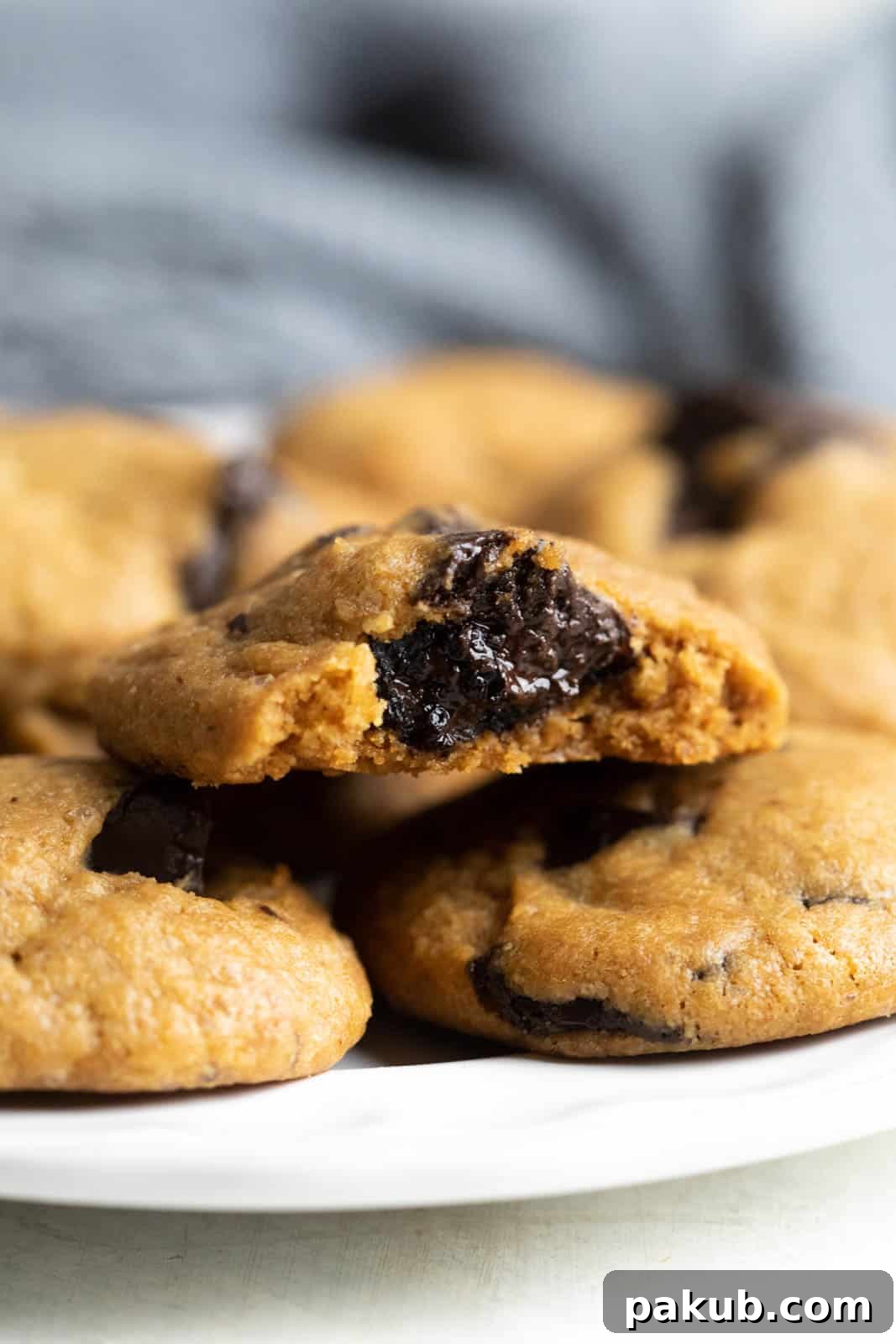 A close-up shot of a single eggless chocolate chip cookie with a bite taken out, revealing its soft, warm interior and molten chocolate chips.