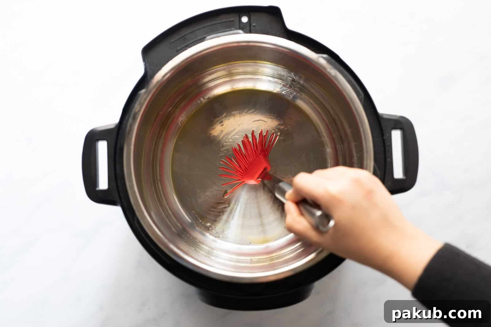 Brushing the Instant Pot steel insert with oil to prepare for bread dough.