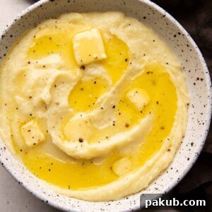 Mashed potatoes served in a white bowl with pools of butter on top