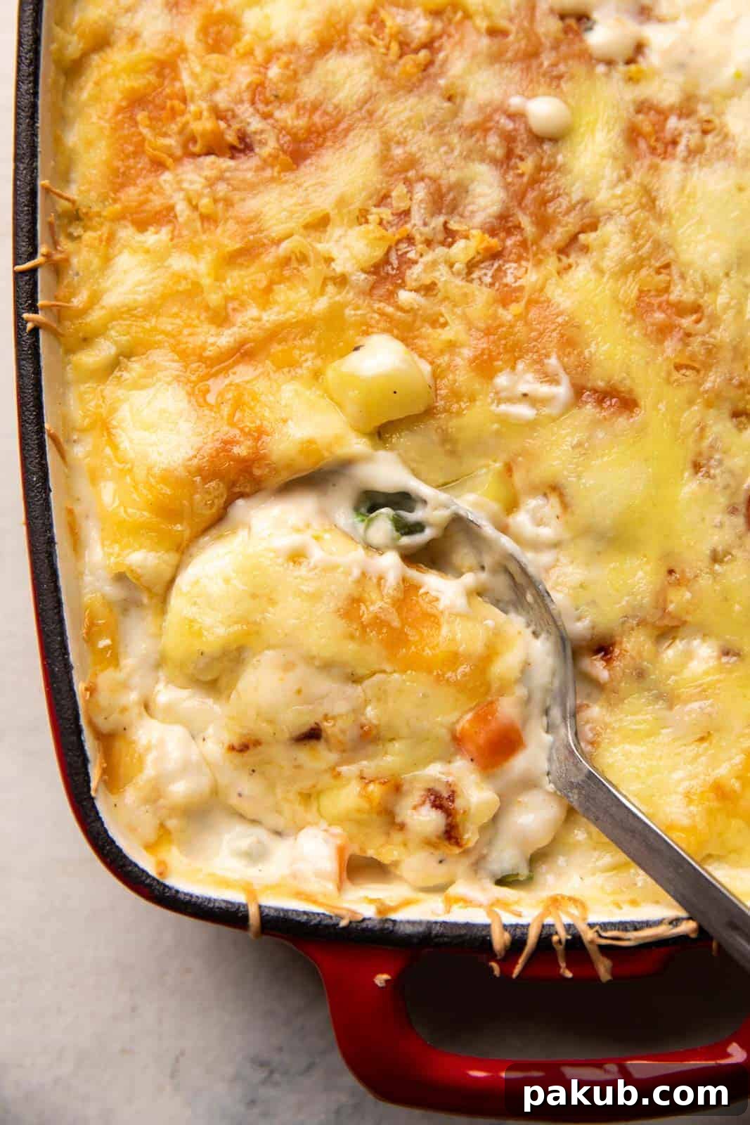 Decadent Creamy Vegetable Gratin 2 Closeup of a picture showing a spoon serving veg au gratin out of the casserole dish, highlighting its creamy texture and golden crust.