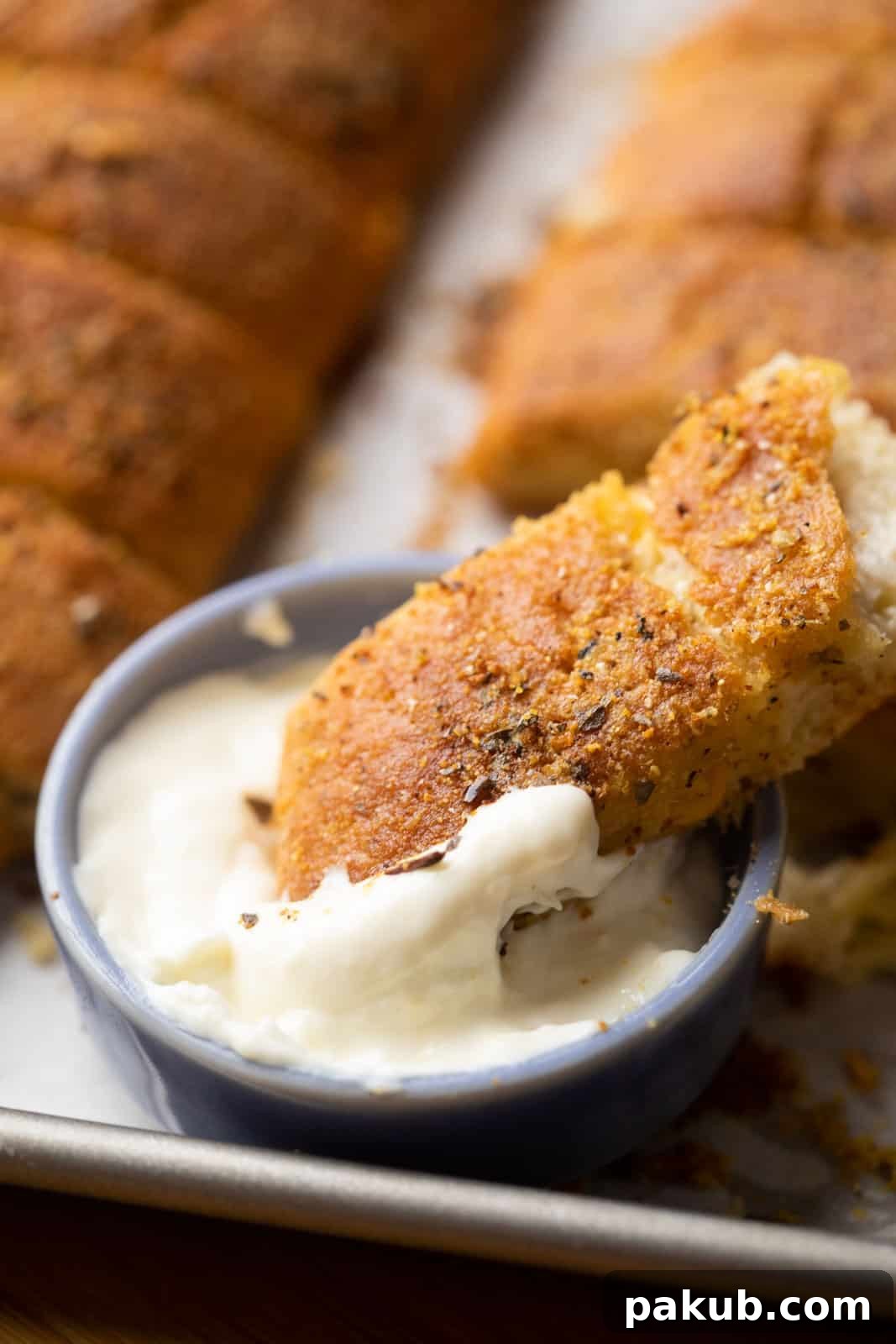 Ultimate Garlic Breadsticks Two Irresistible Styles 4 Closeup of a Domino's style garlic breadstick generously dipped in a rich, warm cheese sauce, highlighting its soft interior.