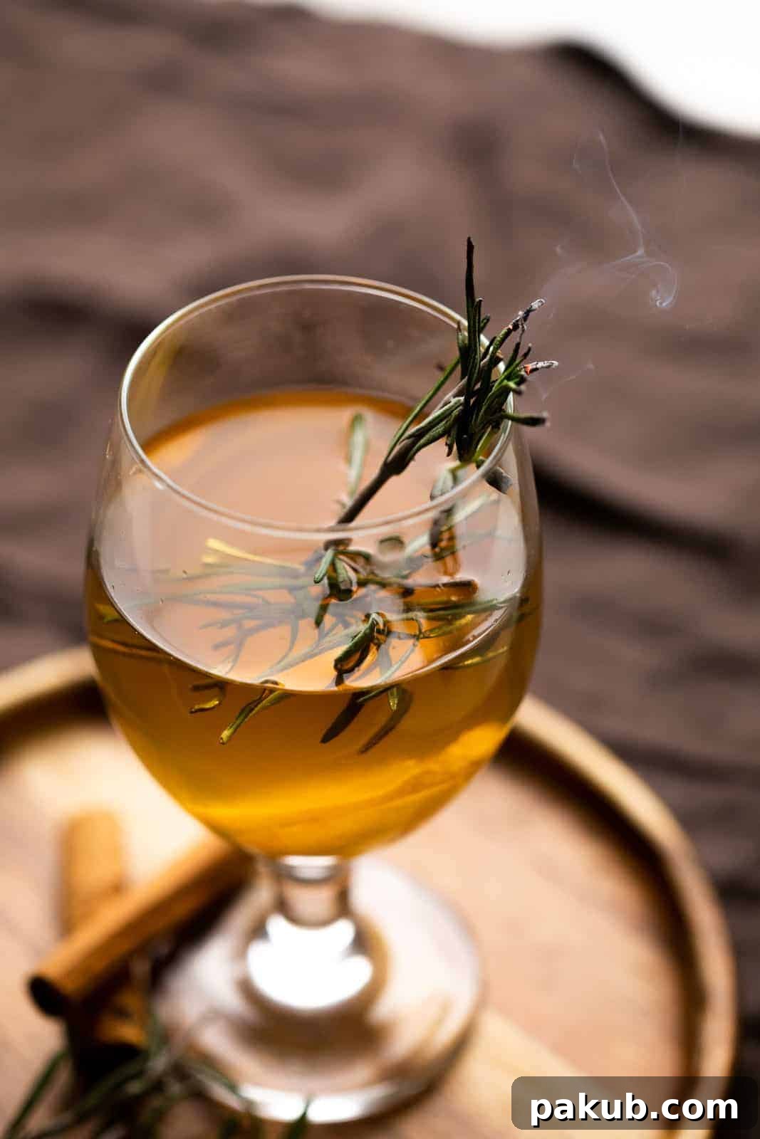 Warm Spiced Elixir 2 A beautifully presented Spiced Hot Toddy in a short-stemmed glass, garnished and ready to be enjoyed on a brown plate.