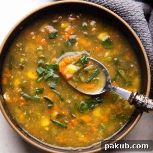 Vegetarian Sweet Corn Soup served in a black bowl with a spoon, highlighting its creamy texture.