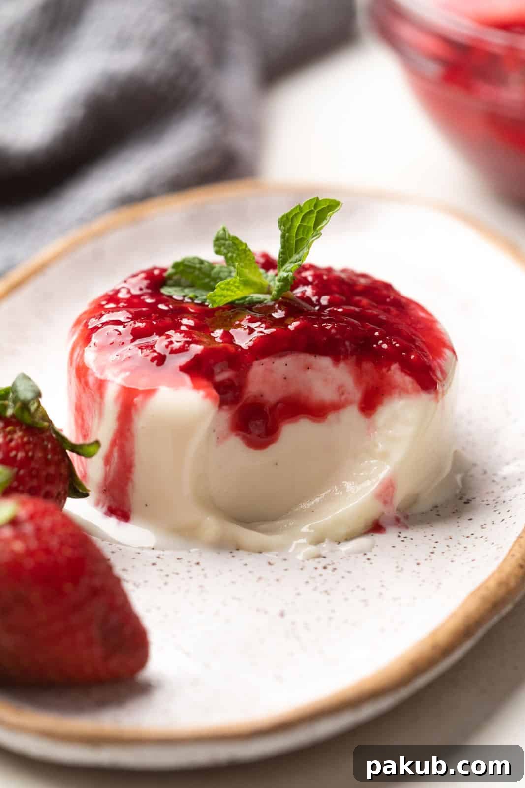 Creamy vanilla bean panna cotta with visible vanilla specks, garnished with fresh raspberries on a white plate