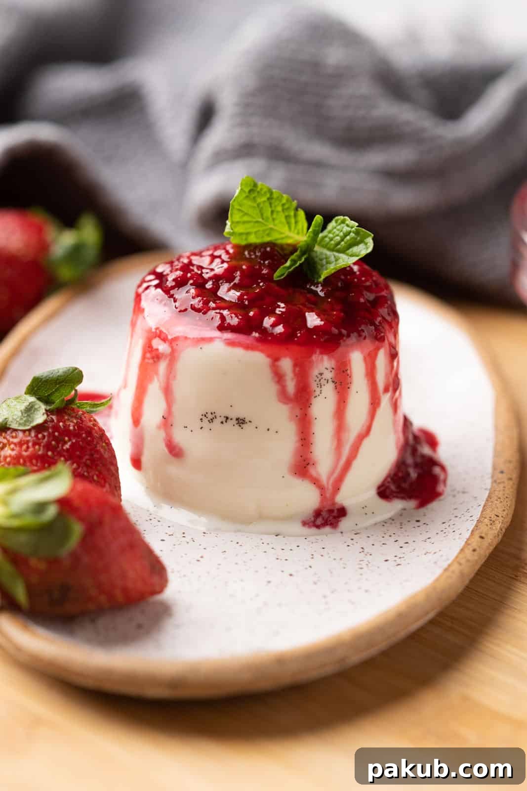 Classic vanilla panna cotta with visible specks of vanilla bean, beautifully plated and topped with a vibrant raspberry coulis