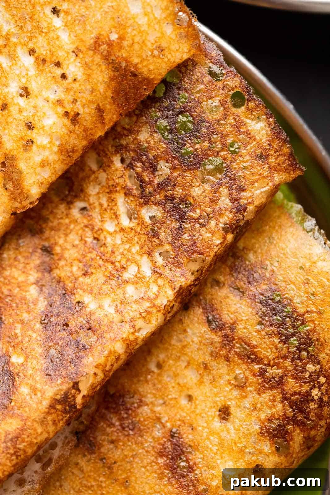 A close-up shot of a golden-brown, lacy dosa spread thinly, highlighting its incredibly crispy texture and delicate appearance, served on a plate.