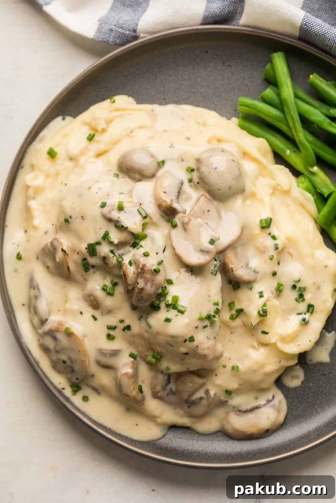 Instant Pot Creamy Mushroom Chicken 2 Instant Pot Chicken in creamy mushroom sauce served over a bed of fluffy mashed potatoes with steamed green beans on a grey plate