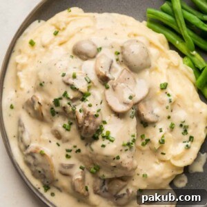 Instant Pot Chicken in mushroom sauce served over a bed of mashed potatoes on a grey plate with steamed green beans