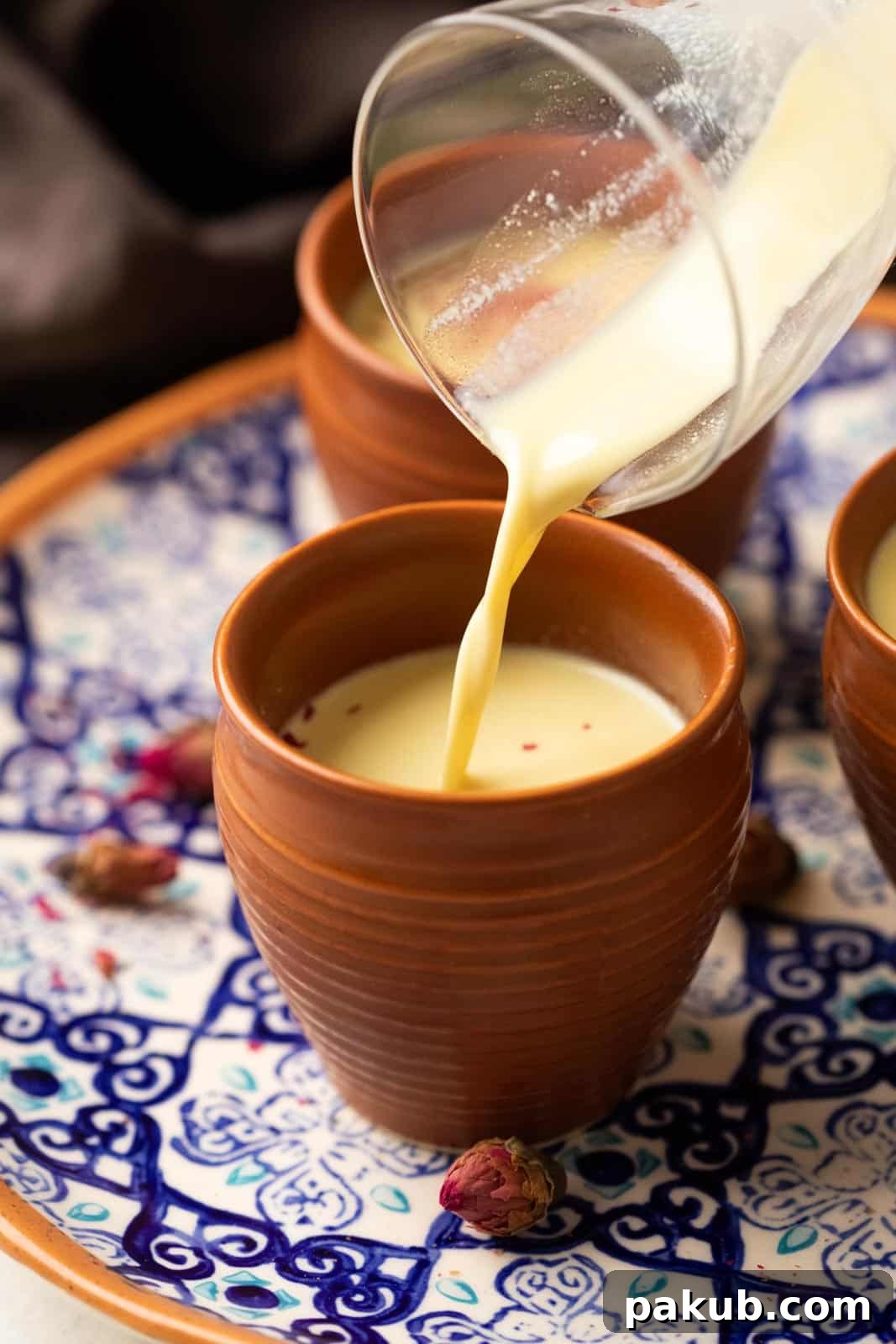 Holi Thandai Masterclass From Scratch 4 Thandai being poured from a glass jar into mud glasses or kullads