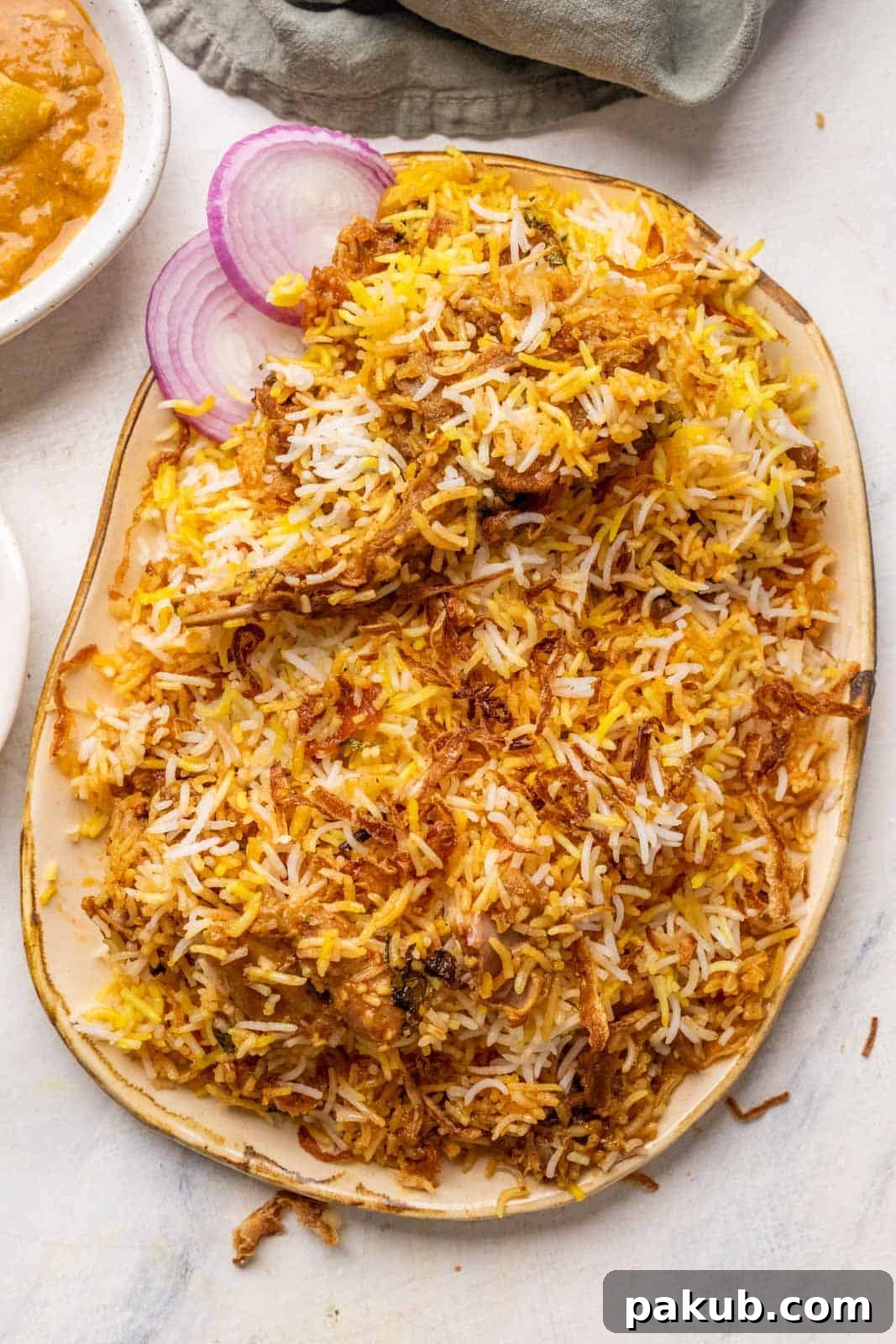 Mouthwatering Mutton Biryani Made Easy 2 Mutton biryani served on a platter with sliced onions, raita and mirchi salan