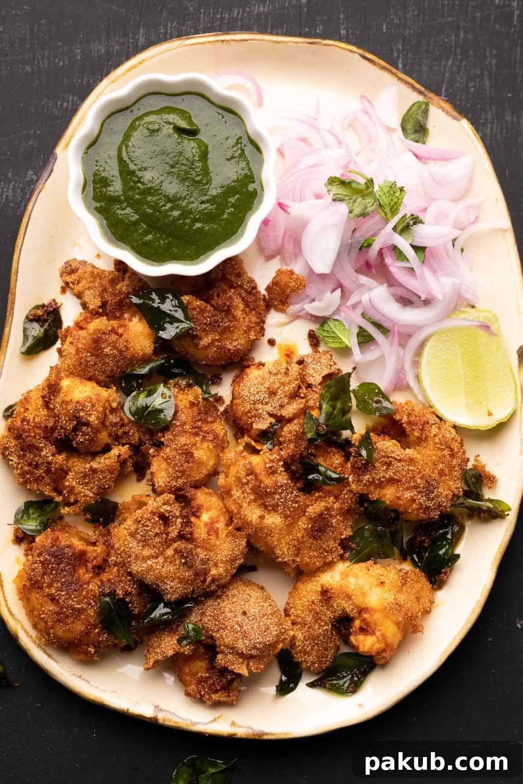 Crispy Mangalorean Rava Prawn Fry 3 Prawn Rava Fry served on a beige platter with a small bowl of chutney and sliced onions on the side, highlighting its golden crispness