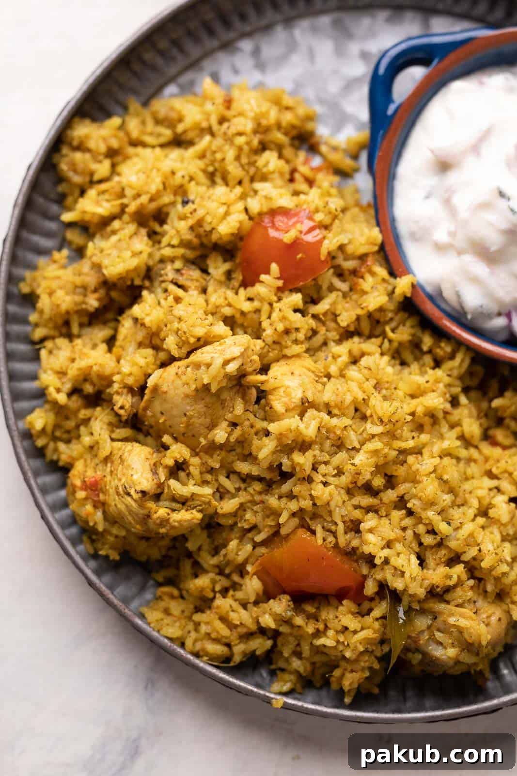 Delicious Chicken Pulao served on a grey plate with a side of raita