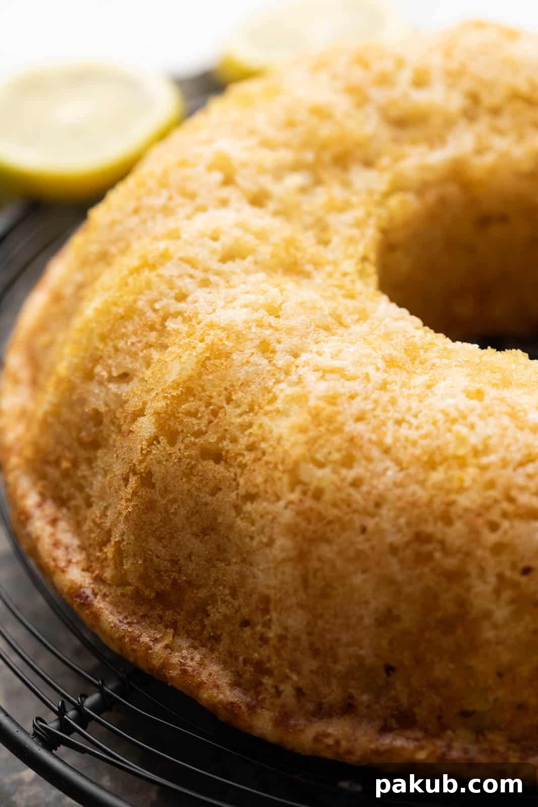 Light & Moist Eggless Lemon Cake 2 Closeup of the top of a beautifully baked, glistening eggless lemon cake, cooling on a wire rack, covered in a bright lemon glaze.