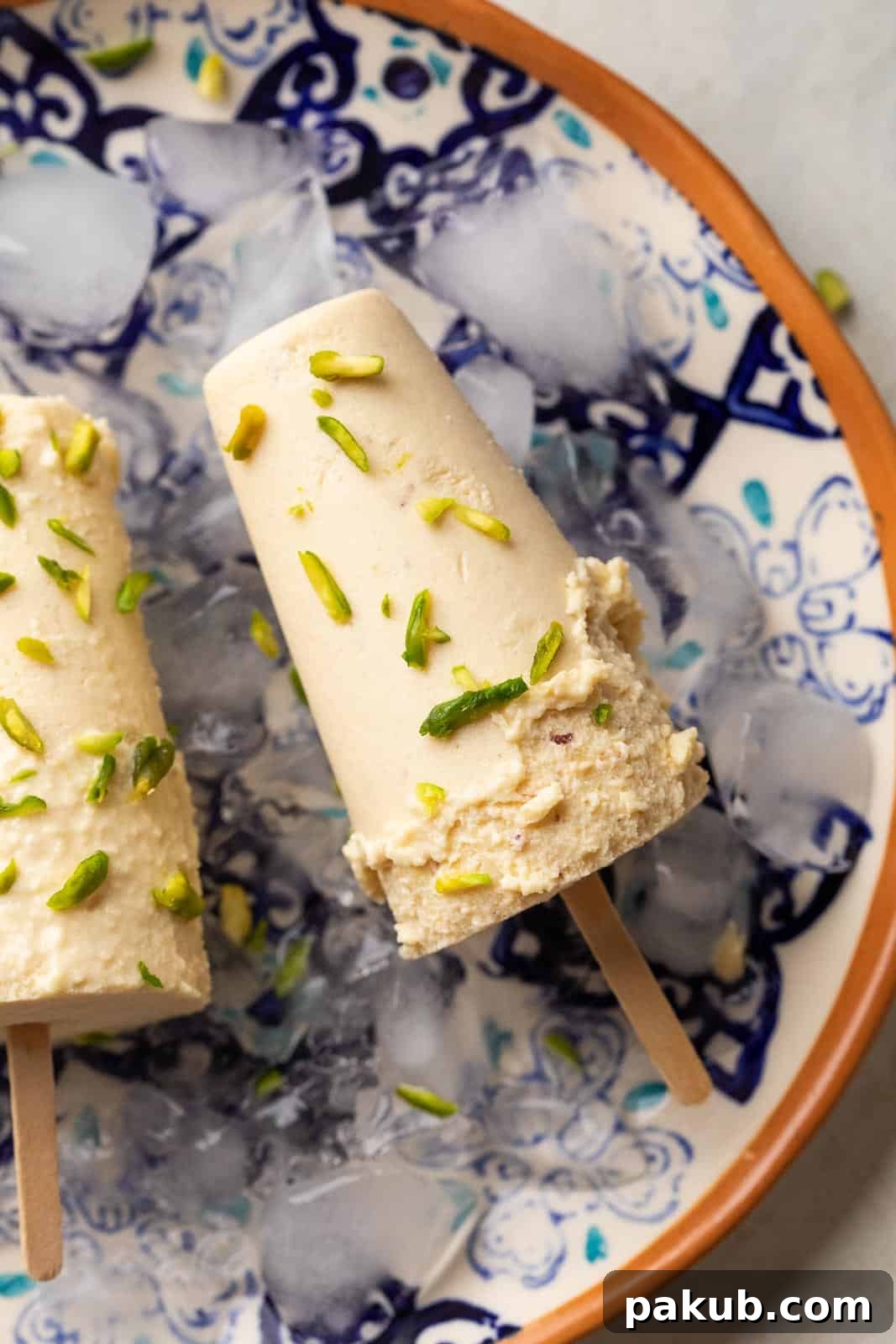 Kulfi Delights: Almond, Cream, and Mango Creations 3 Badam Pista Kulfi served on a plate with some ice to keep it frozen
