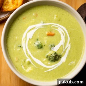 Healthy broccoli soup served in a white bowl with garlic bread on the side, showcasing its vibrant color and creamy texture.