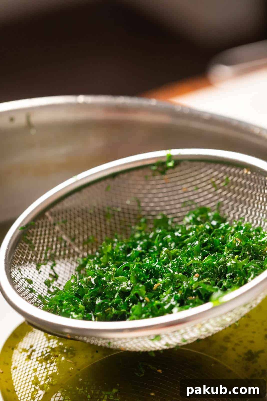 Crispy fried spinach being scooped out of hot oil with a strainer, highlighting its golden texture