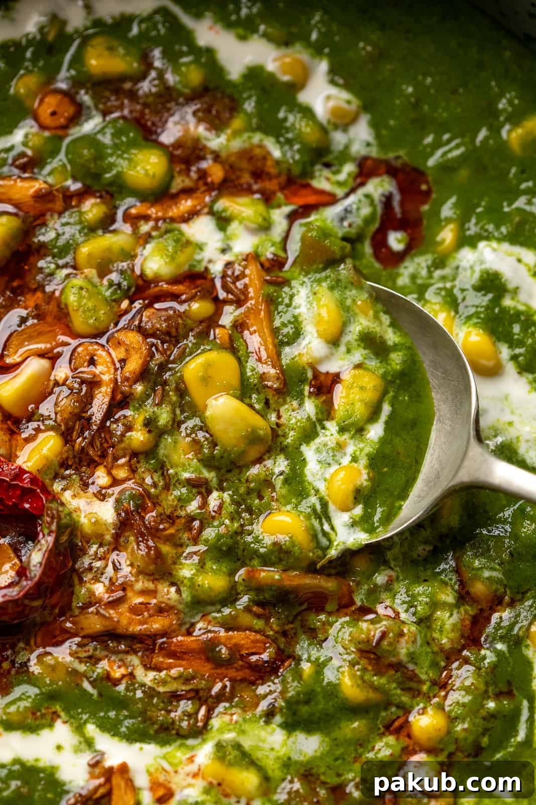 Garlicky Corn Spinach 6 A spoon scooping creamy Lasooni Corn Palak, highlighting the texture and glistening garlic tadka