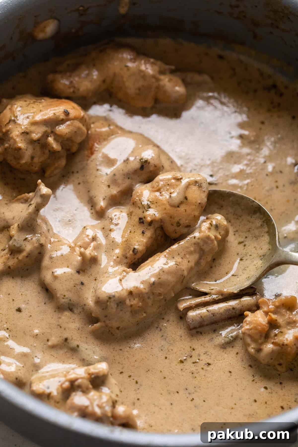 Chicken kali mirch pictured in the pan that it was cooked in with a spoon pooling up the gravy
