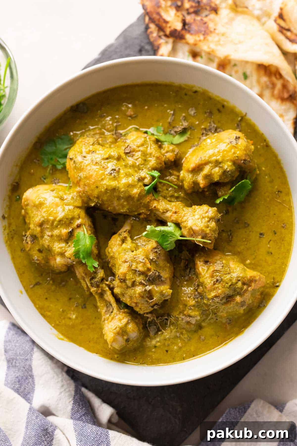 Saag Palak Chicken Recipe 2 A delectable serving of Saag Chicken (Palak Chicken) in a white bowl, accompanied by freshly baked naan bread, showcasing its rich green color and creamy texture.