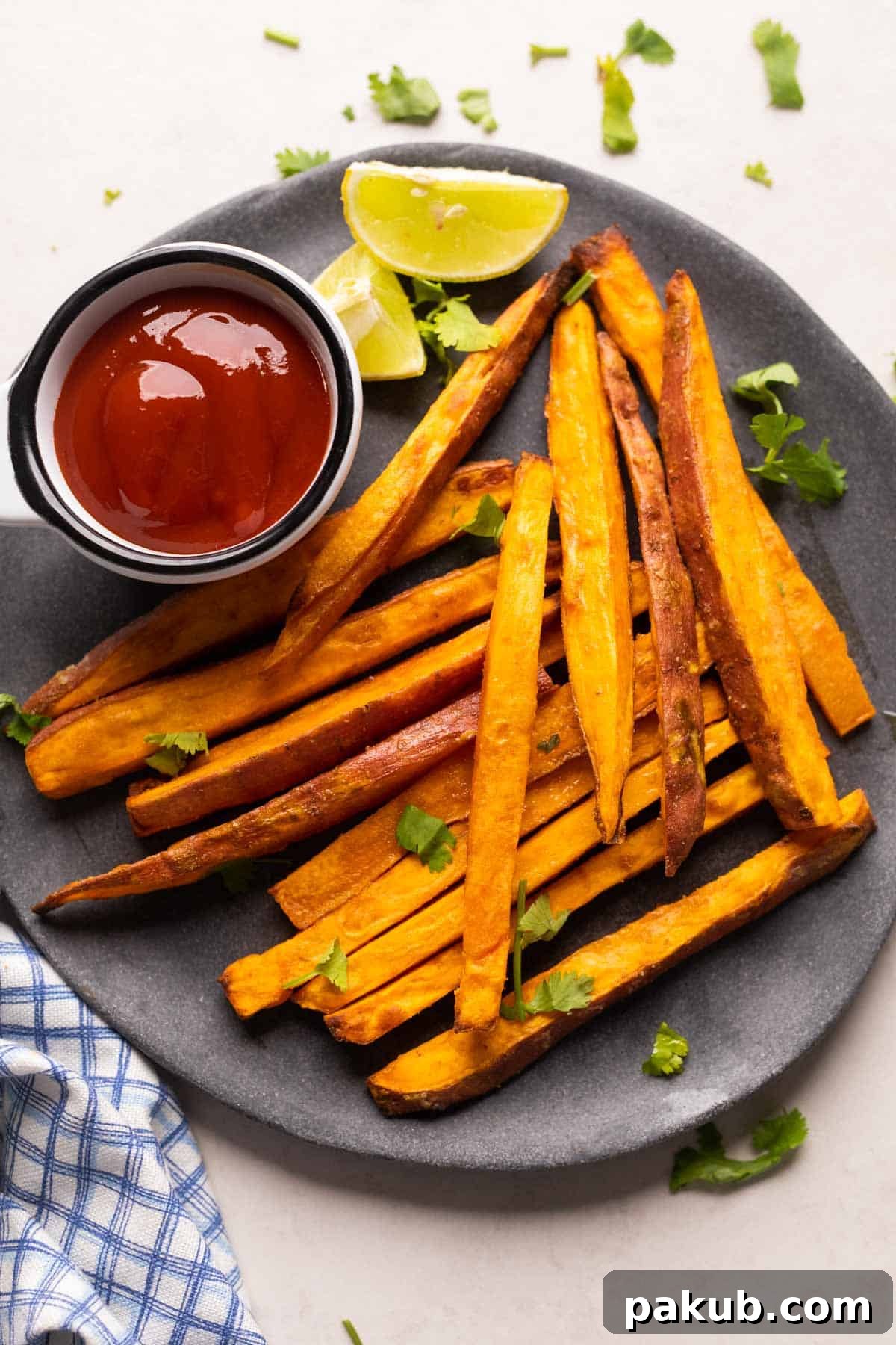 Crispy Air Fryer Sweet Potato Fries served on a grey plate with ketchup and lime wedges on the side