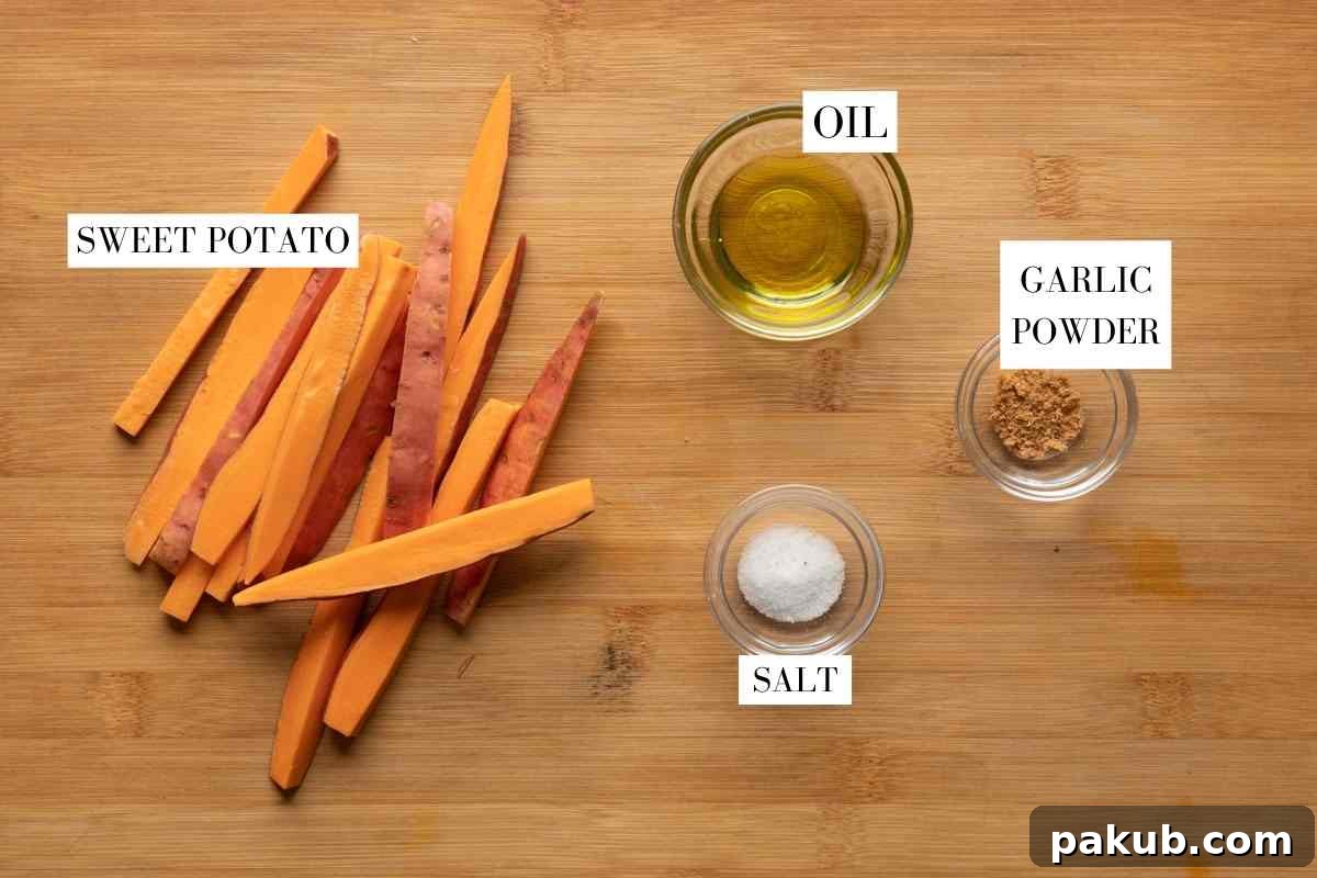 All ingredients laid out for making air fryer sweet potato fries: fresh sweet potatoes, olive oil, salt, garlic powder, paprika.
