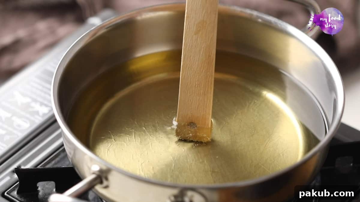 A wooden ladle being dipped into a pan of hot oil to check its temperature using the bubbling method.