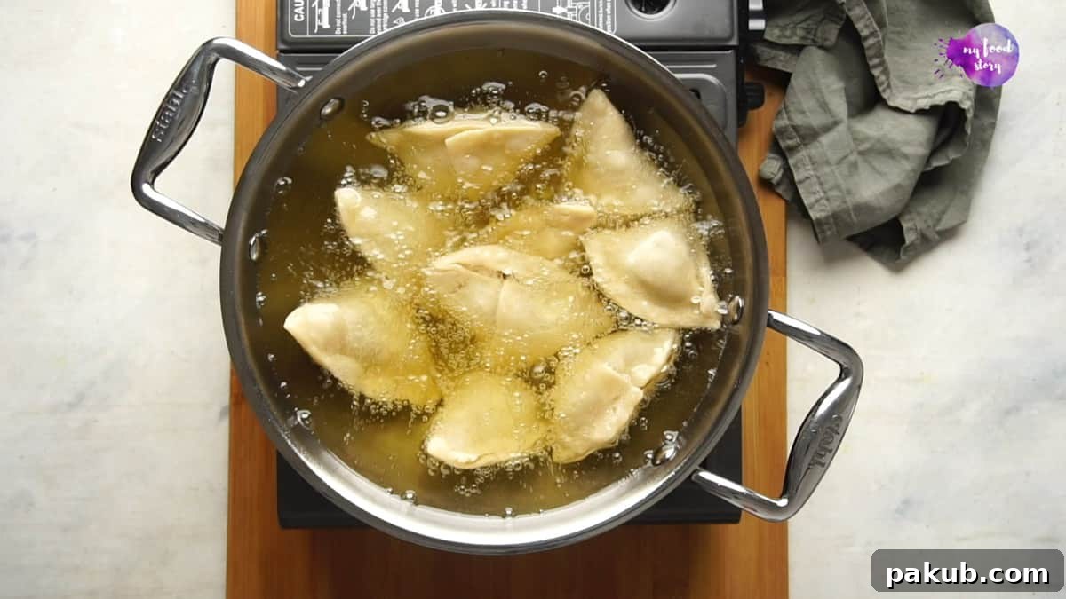 Samosas being fried in a pan of hot oil, demonstrating a perfect deep frying scenario.