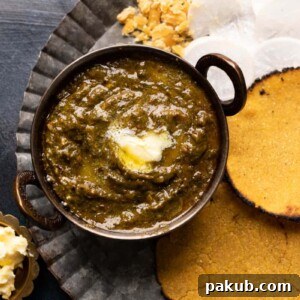 Picture of sarson ka saag served in a small copper kadhai with makki roti on the side