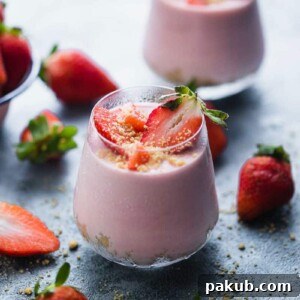 Two visually appealing No Bake Strawberry Cheesecake Jars, adorned with fresh strawberries scattered around them.
