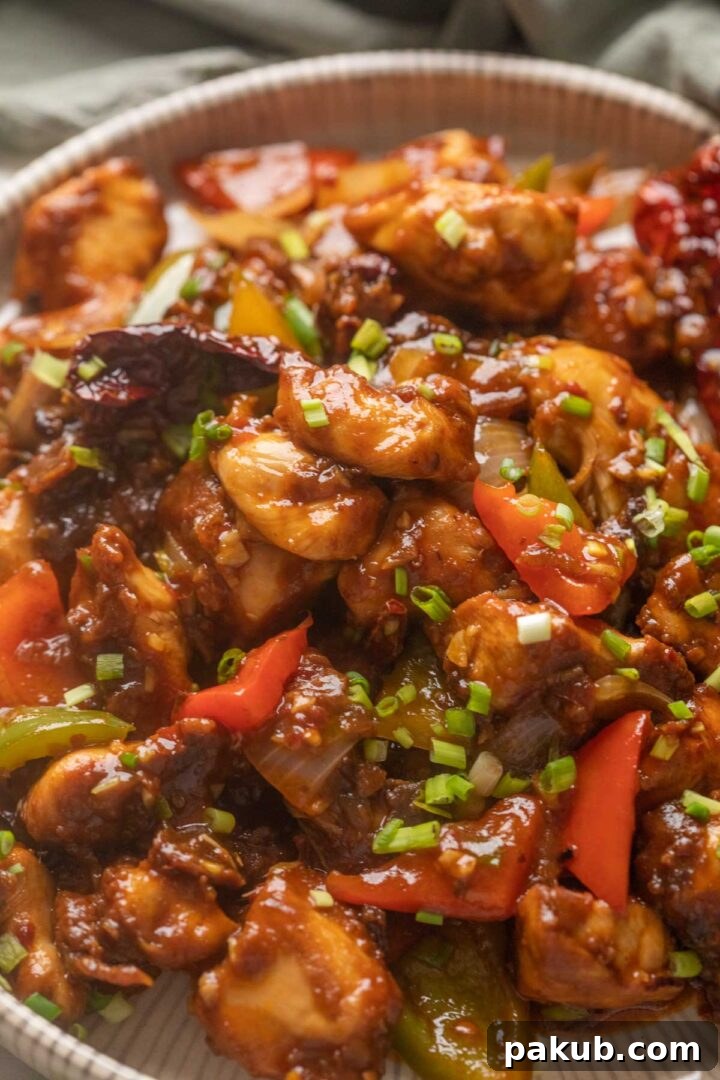 Spicy Szechuan Chicken Stir-Fry 6 Close up of Szechuan chicken served on a white plate, garnished with fresh spring onions.