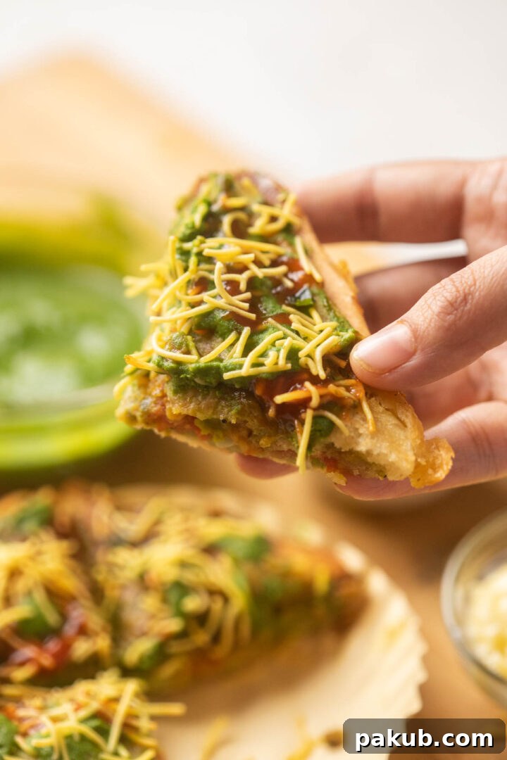 Mumbai Street Toastie 9 A close-up shot of a sliced Bombay Sandwich Toast, revealing the intricate layers of spicy aloo masala, fresh vegetables, and vibrant green chutney, with crunchy sev on top.