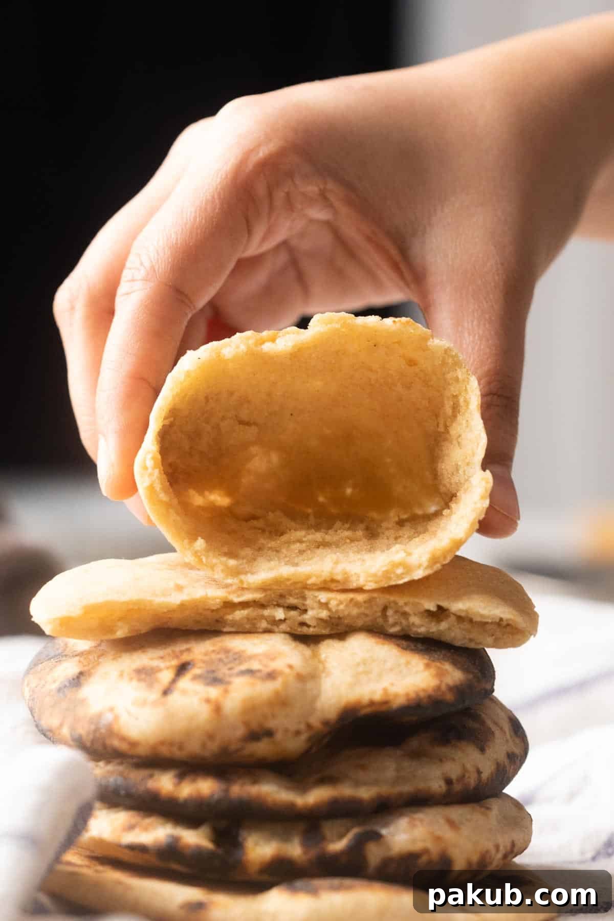 Simple Wholesome Whole Wheat Pita 2 Picture of a hand holding pita open to show the pocket inside, highlighting its perfect puff