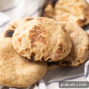 Picture of Whole wheat pita breads kept on a striped white kitchen cloth, freshly baked