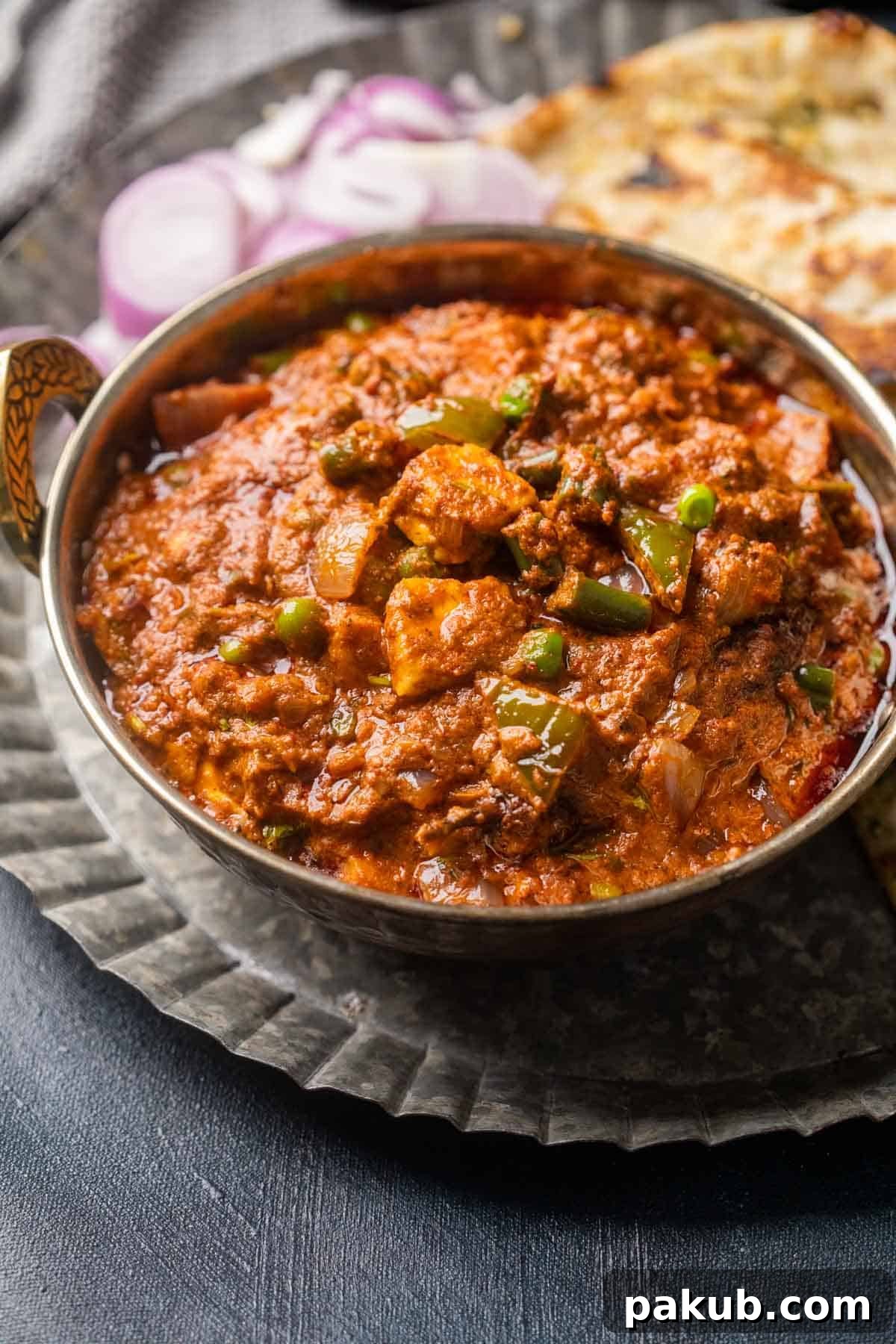 Veg Kolhapuri: Fiery Vegetable Medley 2 Picture of veg kolhapuri served in a copper kadhai on a plate with onions and naan