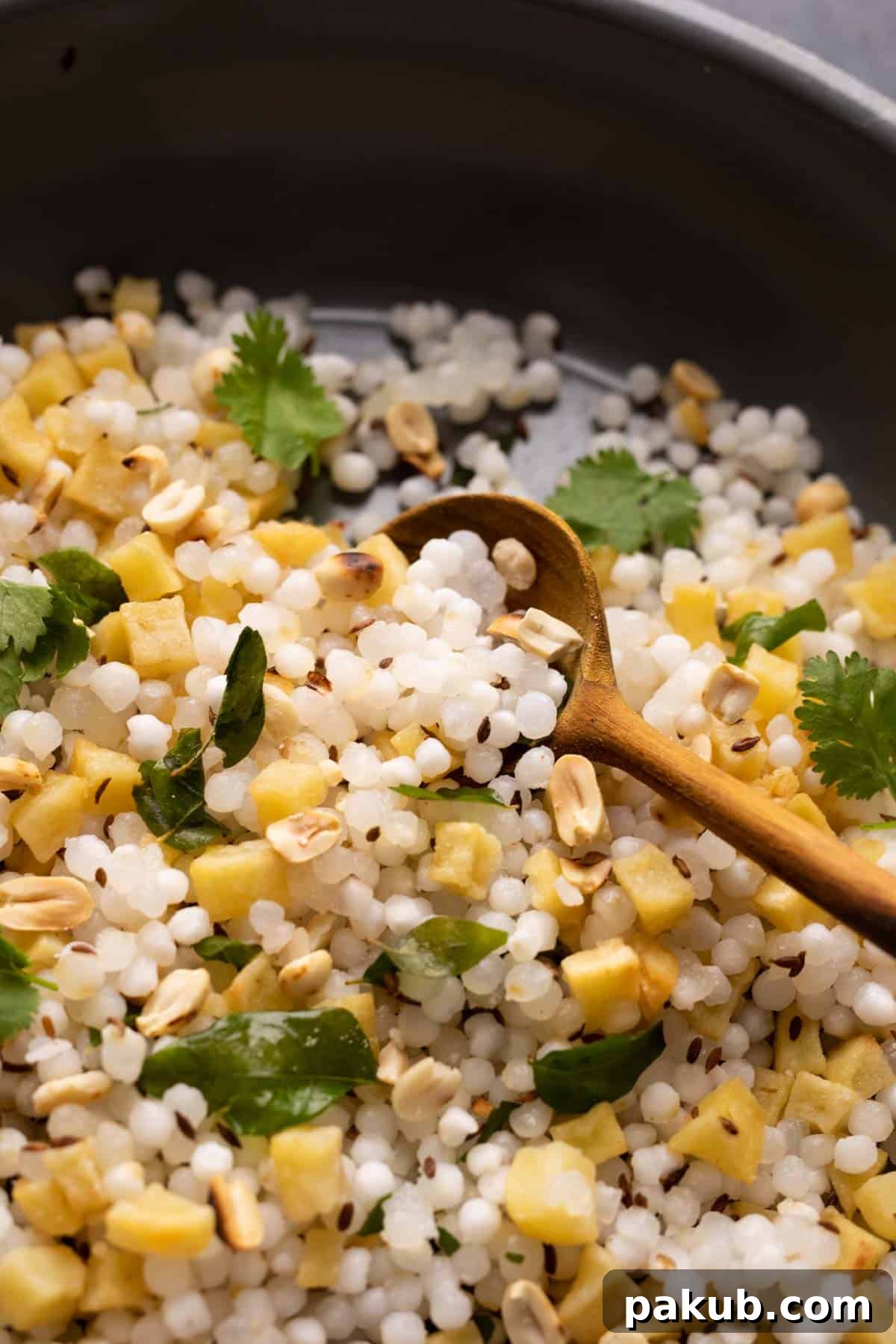 Close-up shot of Sabudana Khichdi cooking in a pan, showcasing the distinct, translucent sago pearls.