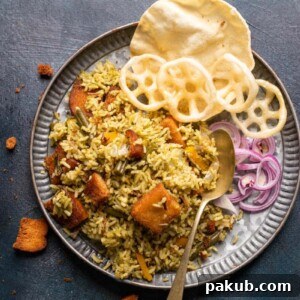 Flavorful Karnataka Rice Bath served with crispy sides and fresh onions
