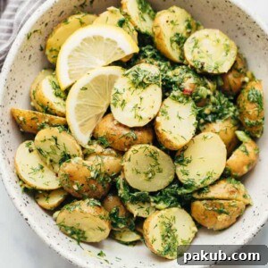 Healthy Lemon Dill Potato Salad, without mayo, served in a white bowl with lemon wedges.