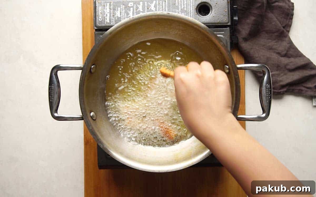Irresistible Baby Corn Crisps 6 Picture showing battered baby corn being deep-fried in hot oil until golden brown and crispy