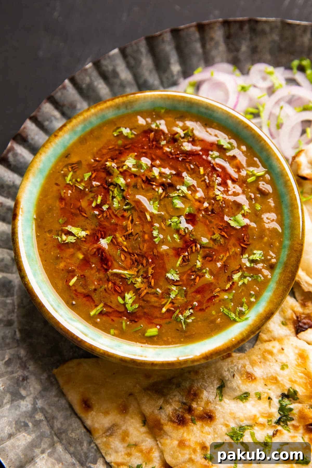 Langar wali dal served in a green ceramic bowl with naan and onions on the side